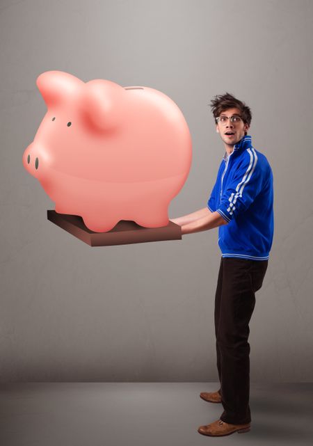Handsome young man holding a huge savings piggy bank