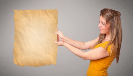 Beautiful young girl presenting old paper copy space