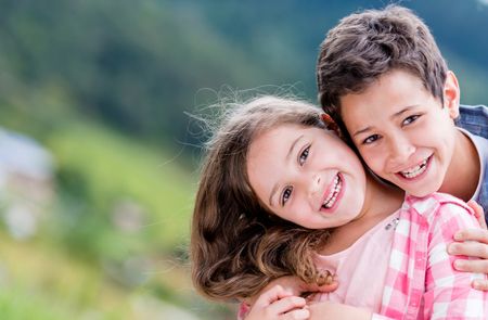 Beautiful portrait of a happy brother and sister outdoors