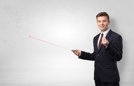 Young businessman with laser pointer and copyspace white wall