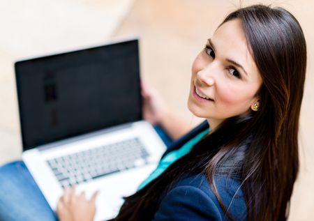 Casual woman working on a laptop computer and smiling
