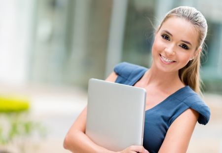 Happy business woman holding laptop and smiling
