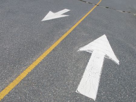 White arrows pointing in opposite directions on street