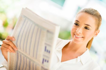 Woman reading the newspaper and looking very happy