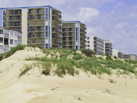Coastal landscape: Row of high-rises with ocean views by dune along beach in Ocean City, Maryland