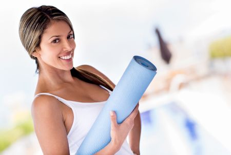 Portrait of a woman holding yoga mat and smiling