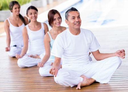 Group of people doing yoga in a studio and smiling