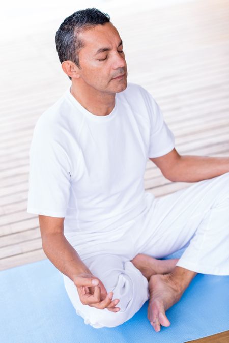 Man meditating while doing yoga with eyes closed