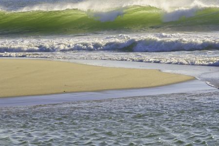 Translucent wave breaking green toward sandy beach in the morning, Cape Cod, Massachusetts