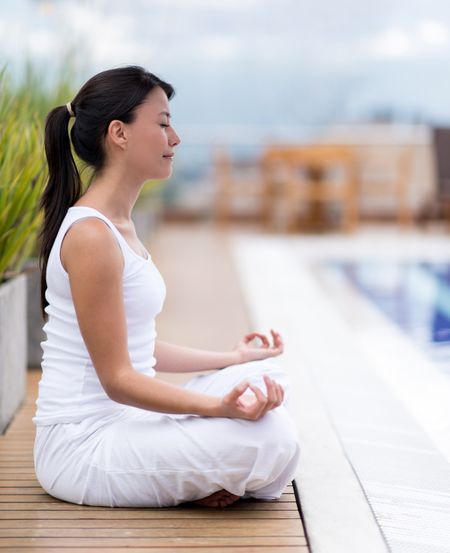Woman meditating outdoors sitting in a yoga position