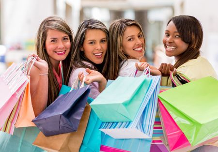 Happy group of female shoppers holding bags and smiling