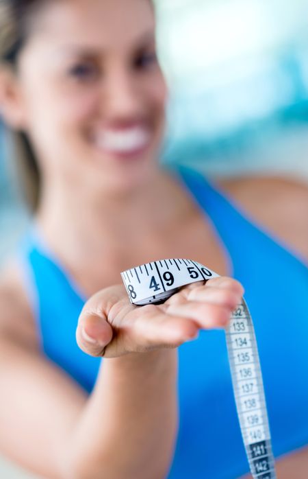 Gym woman loosing weight and holding a tape measure