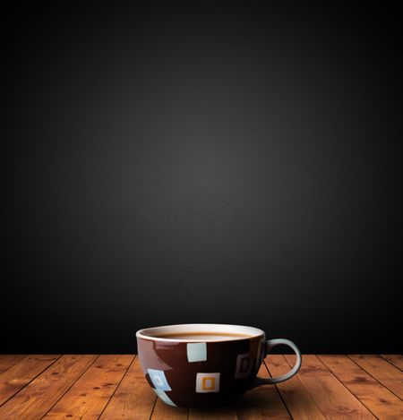Cup of drink on wooden table with dark background