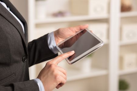 Business woman below chest using tablet in a homey environment