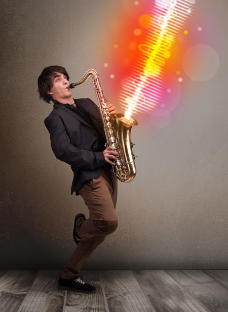 Attractive young man playing on saxophone with colorful sound waves