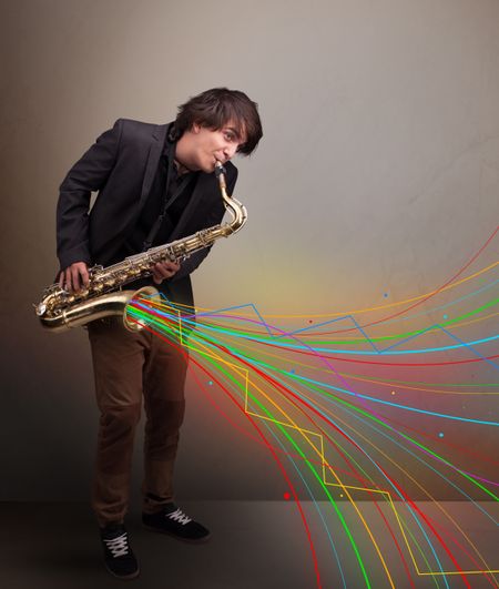 Attractive young musician playing on saxophone while colorful abstract lines exploding