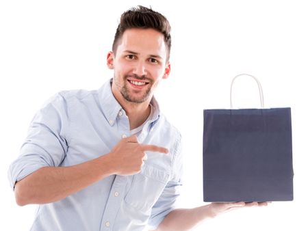 Happy shopping man pointing at a bag - isolated over white 