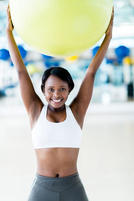 Happy woman doing Pilates with a fitness ball and smiling