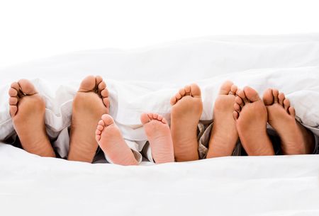 Family in bed with their feet out  - isolated over white 