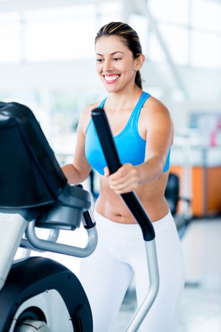 Beautiful woman exercising at the gym on an x-trainer