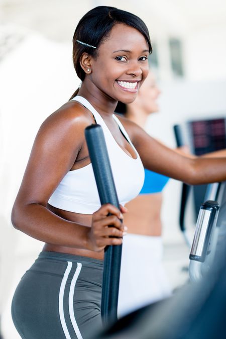 Happy woman exercising at the gym on an x-trainer