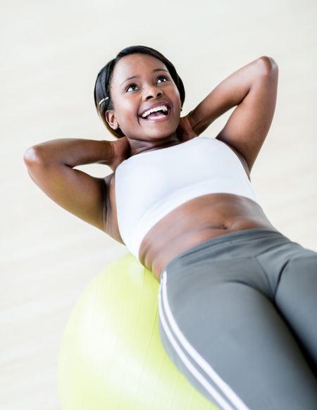 Happy woman at the gym exercising with a Pilates ball
