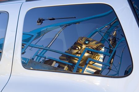 Reflection of huge sphinx mask on carnival ride in rear window of van
