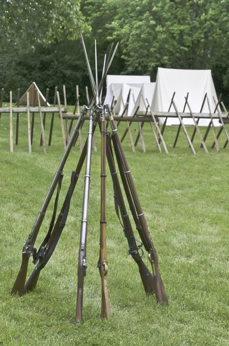 Muskets with bayonets stacked together in Union camp at reenactment of battle in American Civil War (1861-1865), Lombard, Illinois (selective focus)