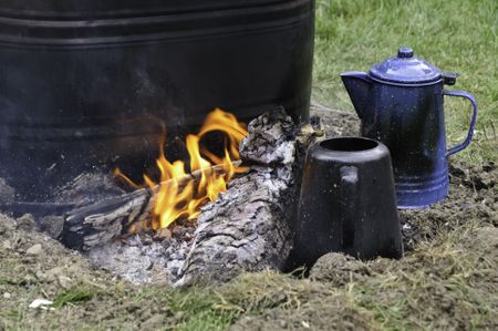Detail of campfire, with burning log between two coffeepots and a tub of water, at Confederate encampment before reenactment of battle in American Civil War (1861-1865)