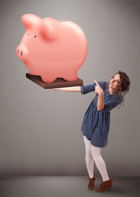 Beautiful young girl holding a huge savings piggy bank