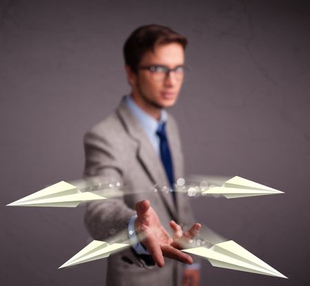 Handsome young man throwing origami airplanes