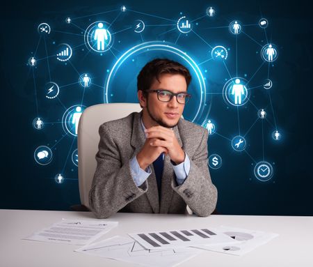 Young businessman sitting at desc with social network icons