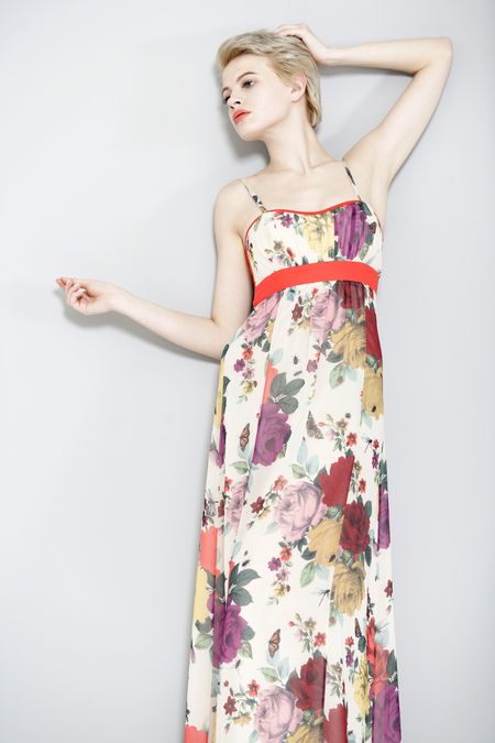 Beautiful young woman leaning against a wall in a long summer dress.