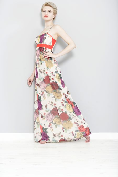 Beautiful young woman leaning against a wall in a long summer dress.