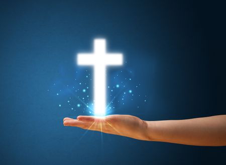 Young woman holding a glowing cross in her hand