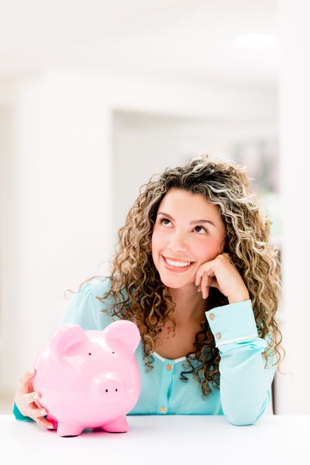 Thoughtful woman with her savings in a piggybank 