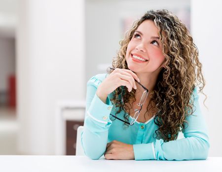 Thoughtful business woman sitting on her desk at the office