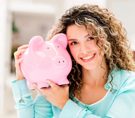 Woman holding a piggybank and looking very happy 