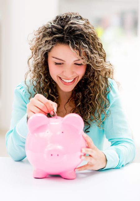 Happy woman putting savings in a piggybank 