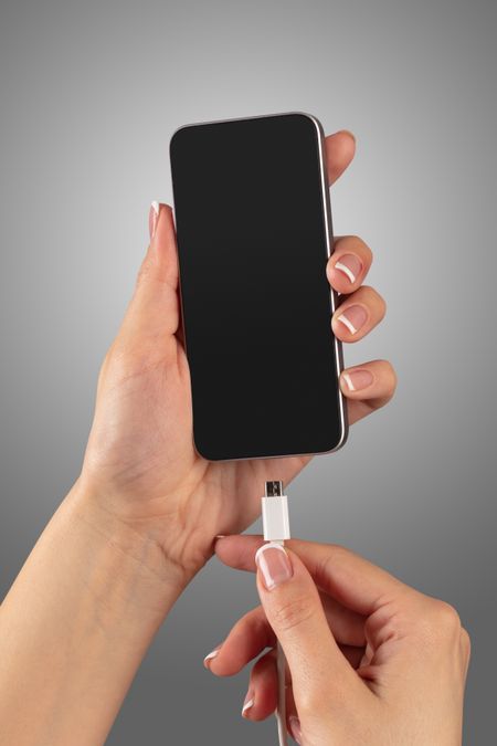 Close-up view of hand charging smartphone