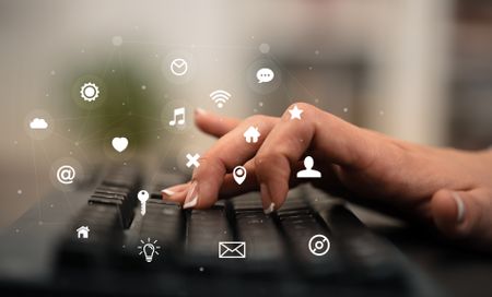 Business woman hand typing on keyboard with application icons around