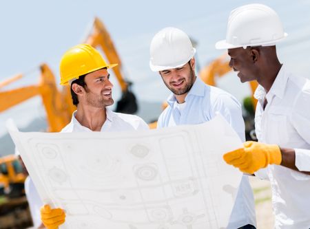 Group of architects at a construction site looking at blueprints 