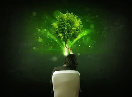 Young businessman sitting in office chair with a glowing tree and letters above his head