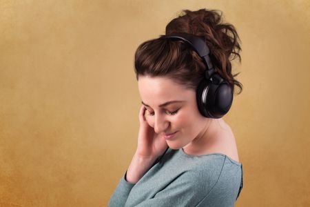 Pretty young woman with headphones listening to music with empty space