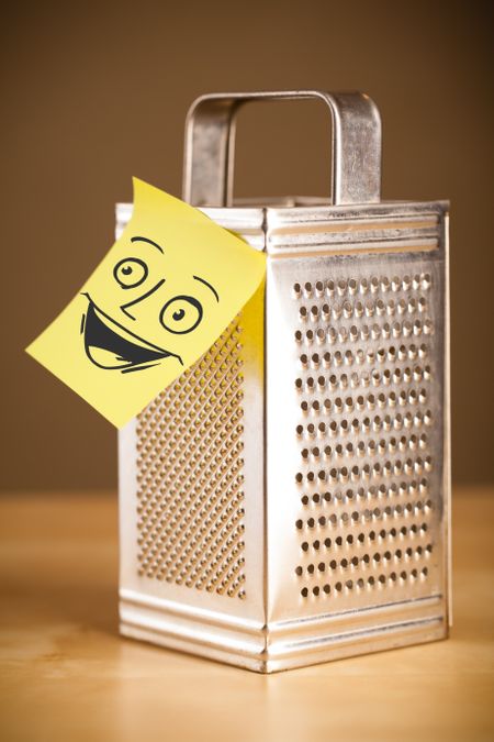 Drawn smiley face on a post-it note sticked on a grater