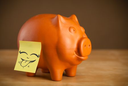 Drawn smiley face on a post-it note sticked on a piggy bank