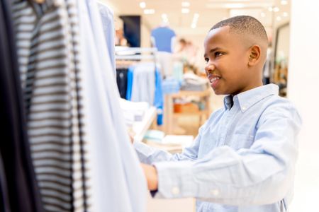 Happy boy shopping for clothes at a retail store 