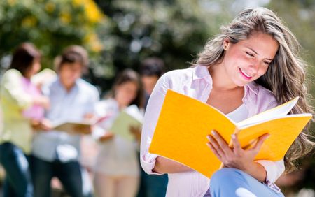 Happy woman studying outdoors reading her notebooks 