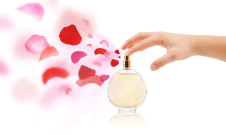 close up of woman hands spraying rose petals from beautiful perfume bottle