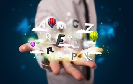 Young business man in suit presenting magical clouds with letters and balloons concept